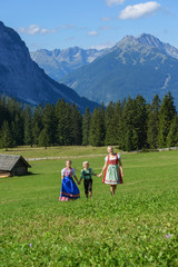 Young Bavarian family in a beautiful mountain landscape. Happy mother und children  wearing a...