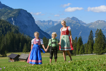 Fototapeta na wymiar Young Bavarian family in a beautiful mountain landscape. Happy mother und children wearing a traditional Bavarian clothes
