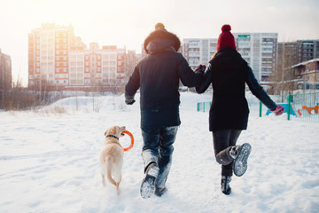 Fototapeta na wymiar couple is running home with his dog. Concept winter walk.