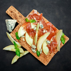 italian food with melon, prosciutto and cheese on cork cutting board
