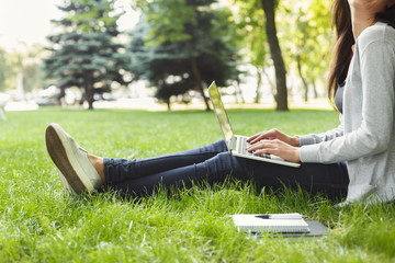 Young pensive woman using laptop in park