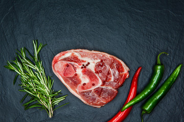 Raw juicy meat steaks ready for roasting and vegatables on a black board background. Space for text
