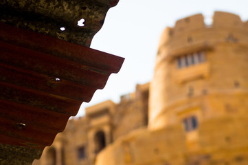 Roof of shed with the sandstone walls of a fort in the distance and blurred out. Shows a comparison...