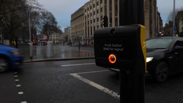 Pedestrian presses the crossing button in able to cross the street. Tilt close up.