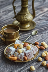 Oriental Arabian sweets with different nuts a cup of coffee. Eastern sweets. Traditional Turkish delight (Rahat lokum) on a wooden background. View from above.
