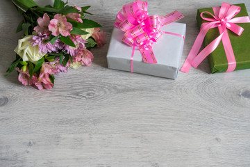Colorful bouquet of roses, chrysanthemum and alstroemeria flowers with gift boxes on wooden...