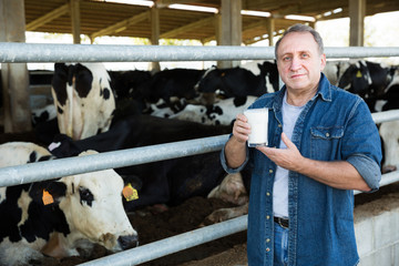 Male farmer is holding glass of milk