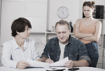 Fototapeta premium Smiling parents are reading utility bill with their adult daughter