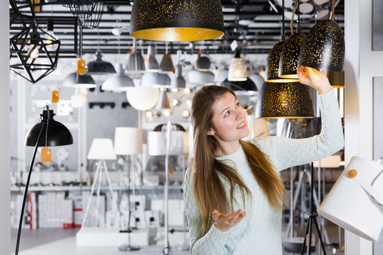 Girl buying plummed lamp in the modern furniture store