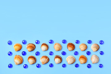 Pattern of sea shells and glass beads on a blue background. Flat lay, top view. Copy space