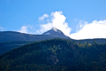 Fototapeta premium Clouds resting on snow capped mountian
