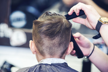 Barber shop. Barbershop hairdresser makes hairstyle to a boy.