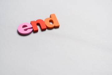 End, word written on white background with colorful polystyrene letters.