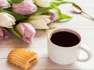 Coffee Cup with biscuits and tulips on a wooden table