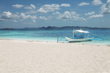 Fototapeta na wymiar The boat at a deserted beach on a hot day near the Philippine Islands