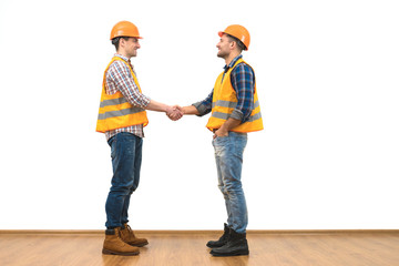 The two engineers handshake on the white wall background