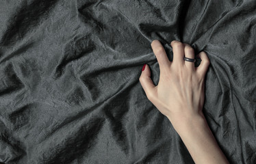 woman's hand holding a satin sheet, a moment of pleasure