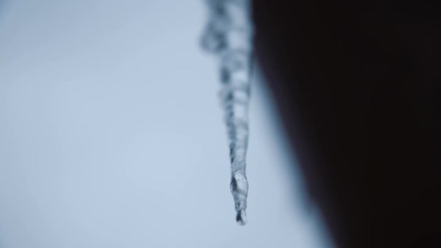 From below view of crystal clear cold icicle on roof corner.