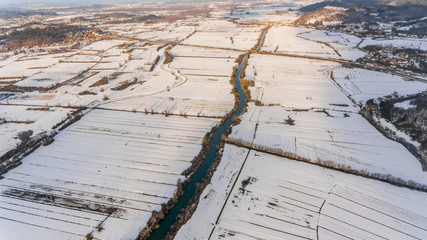 Aerial view of a river flowing through winter countryside.