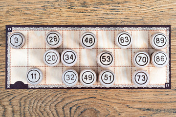 Lotto board game card is completely closed with barrels with numbers on a wooden table