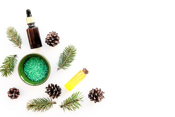 Pine spa cosmetics, products for skin care. Fir essential oil and green aromatic spa salt near branches and cones on white background top view copy space