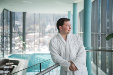 Man standing next to a pool in a robe and relaxing