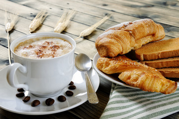 Traditional Italian breakfast with cappuccino and croissants on a rustic wooden table