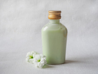 Cosmetic bottle container with white flowers. Natural organic beauty product concept.

