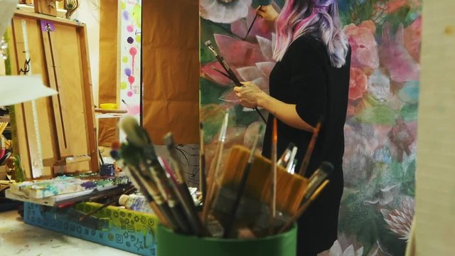 artist working with the big painting at workshop, hipster woman painter with colorful hair 