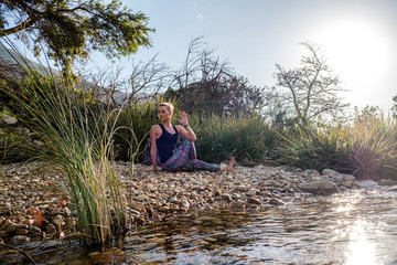 female performing yoga pose with scenic mountain and river background