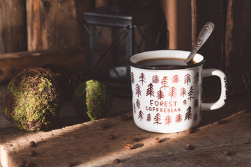 White ceramic cup of coffee on old books on rustic wooden background with cones