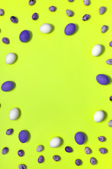 Frame of white, violet and quail easter eggs on yellow background, copy space. Healthy food concept. Top view, flat lay. Happy Easter concept