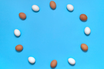 Frame of white and brown eggs on blue background, copy space. Healthy food concept. Top view, flat lay. Easter eggs. Happy Easter concept