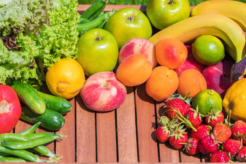 Various vegetables and fruits on a wooden tray against a background of green grass