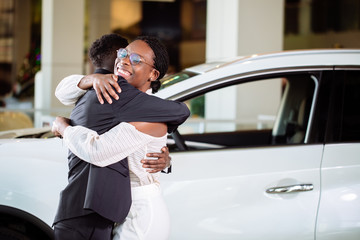 Smiling couple hugging and smiling at camera at new car showroom © alfa27