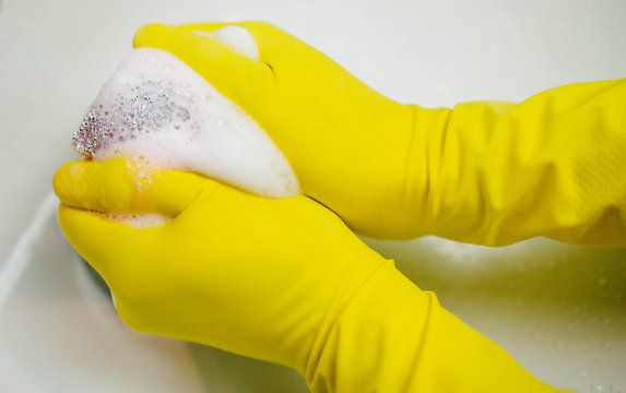 hands in yellow gloves keep the sponge in the foam
