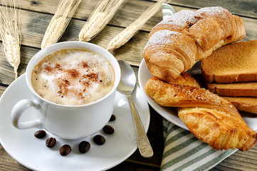 Traditional Italian breakfast with cappuccino and croissants on a rustic wooden table