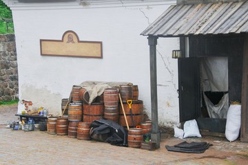 Interesting view for tourists. A variety of wooden wine barrels with metal hoops are near white wall old craft workshop the production cooperage products.