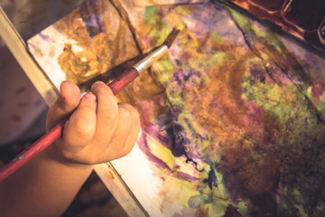 Creative child painter hand with paintbrush abstract paint concept early child art development in art school
