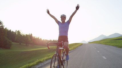 LENS FLARE: Professional biker raising his arms victoriously after winning race.