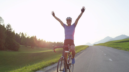 SUN FLARE: Pro cyclist cheerfully rides road bike with no hands after victory.