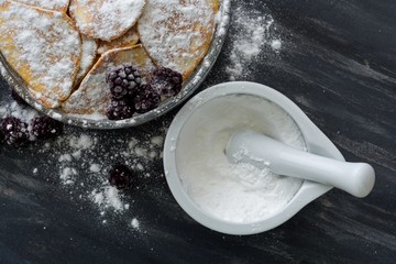 Homemade pancakes with blackberries, powdered sugar. Dark background.