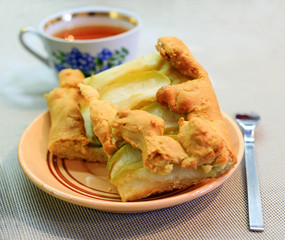 Apple pie piece and cup of tea on gray table background.
