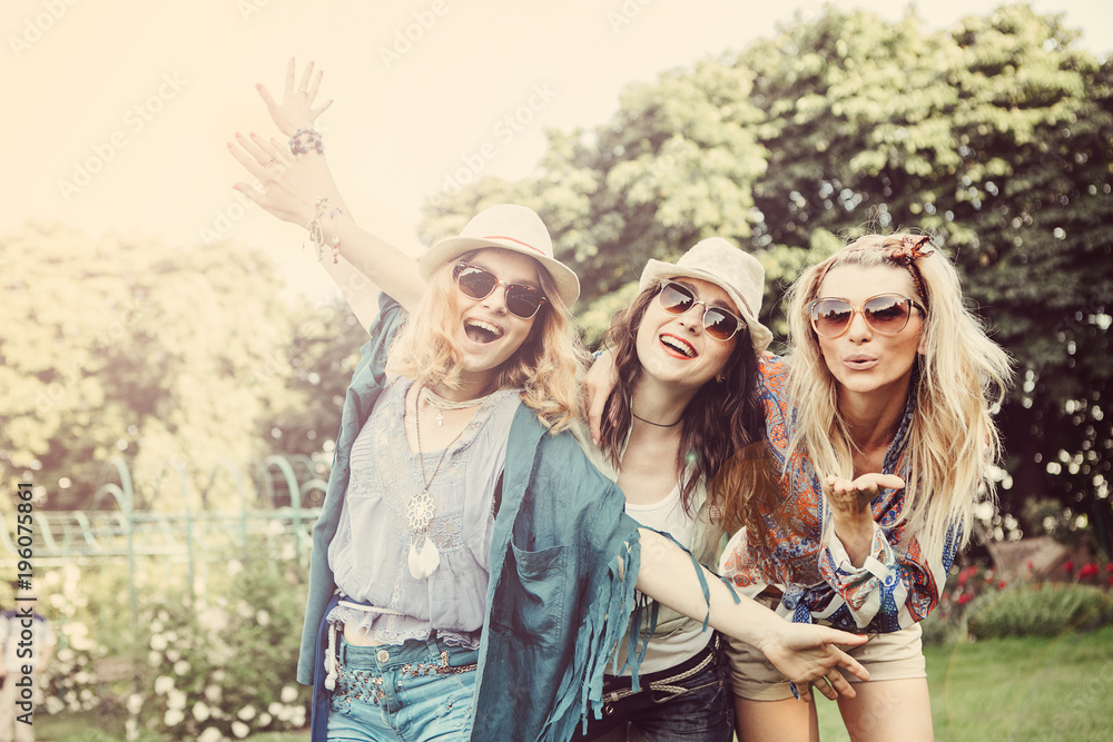 Wall mural Happy friends in the park on a sunny day . Summer lifestyle portrait of three hipster women  enjoy nice day, wearing bright sunglasses. Best friends girls having fun, joy. Lifestyle