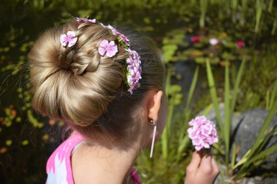 A Blonde Young Girl, Hairstyle: Big Braided Bun With Pink Flowers