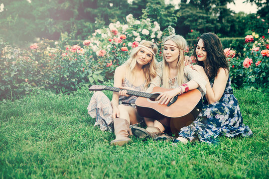 Summer holidays, vacation, travel and people concept - smiling young hippie women with guitar playing music. Funny time for the best friends. Lifestyle. Boho style.