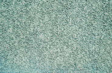 Obraz premium The texture of the plastered surface with a fine gravel of gray-green color.