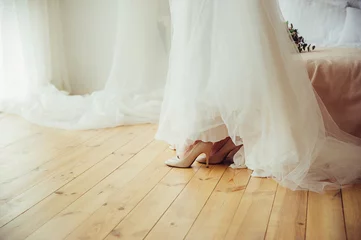 Foto op Plexiglas A bride in wedding dress and shoes on wooden floor © Kalinova Olena
