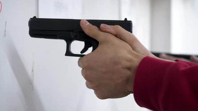 Instructor teaches a man to handle a weapon or gun. Close up of male hands with gun while training with instructor. Close up of man's hand reloading gun