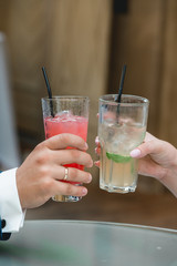 gorgeous bride and groom toasting with alcoholic cocktails, wedding day. hands holding glasses